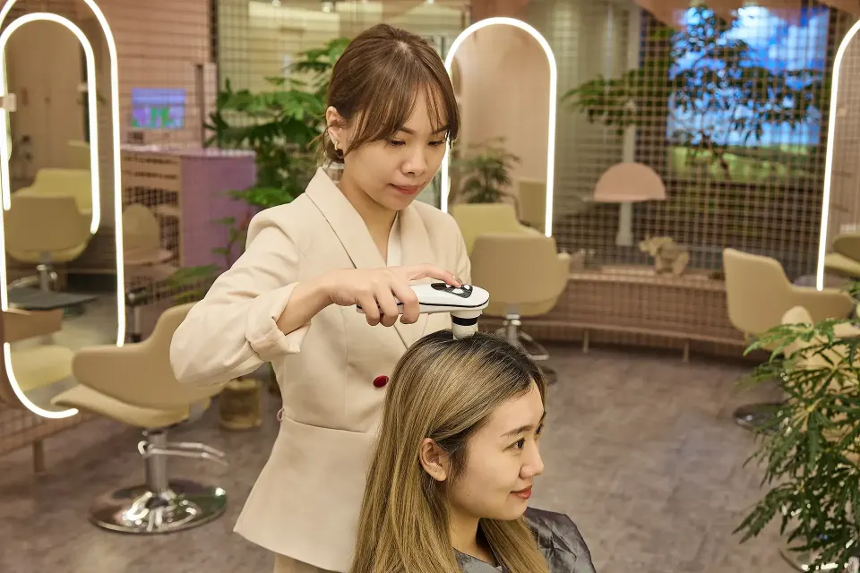 A TrichoLab specialist performing a magnified scalp analysis scan on a client